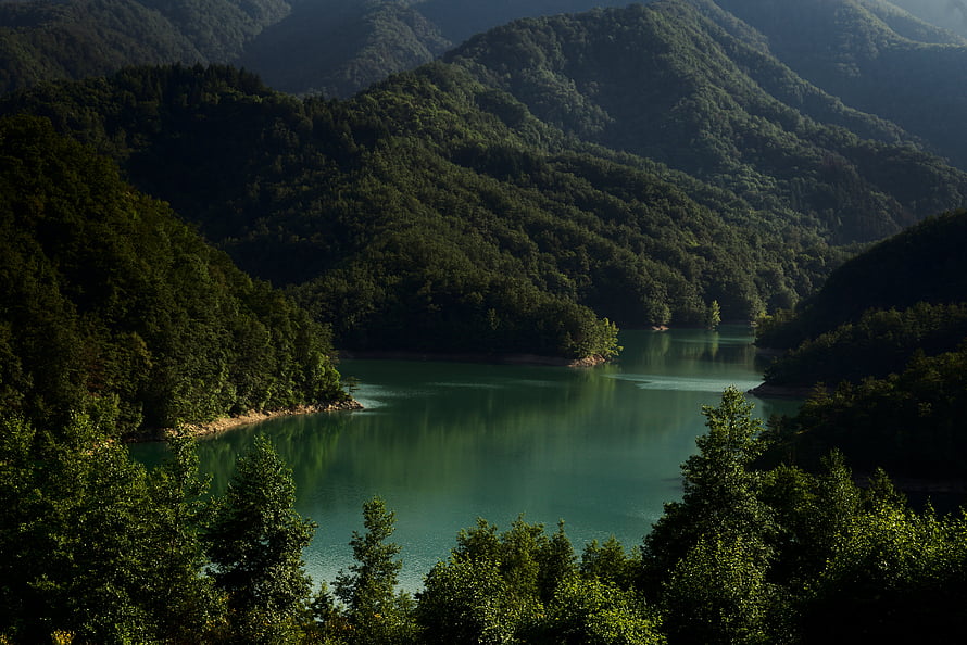 Serene Turquoise Lake Nestled Among Lush Forested Mountains in Italy HD wallpaper
