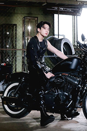 Jungkook from BTS posing in black leather on a Harley-Davidson motorcycle in an industrial garage setting HD phone wallpaper