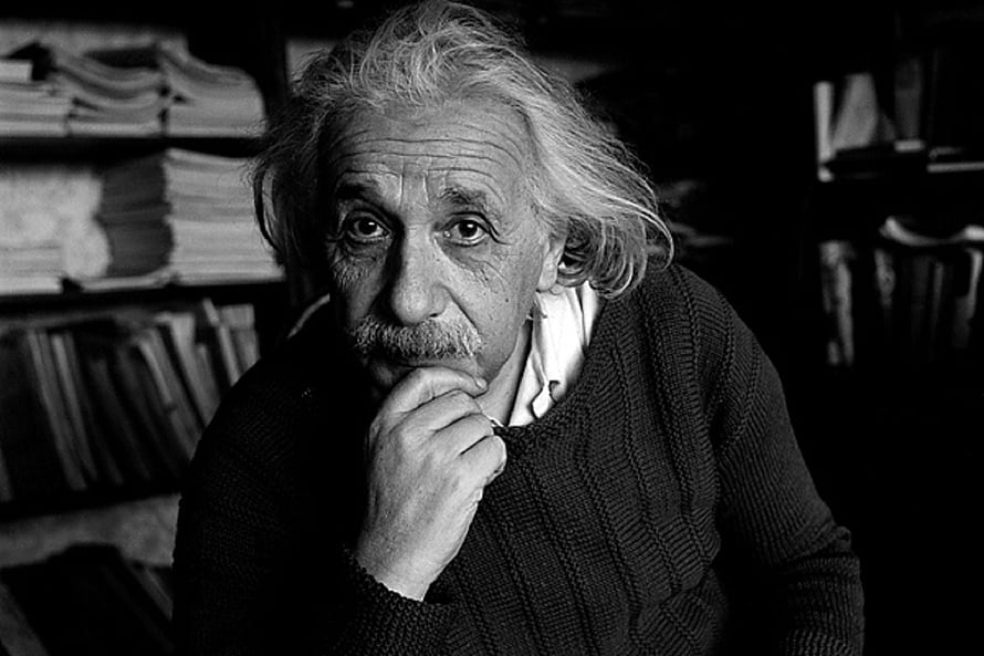 Albert Einstein in a Contemplative Black and White Portrait with Bookshelves HD wallpaper