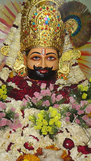 Khatu Shyam Ji adorned with vibrant floral garlands and ornate golden crown HD phone wallpaper
