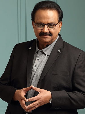 S. P. Balasubrahmanyam in a dark blazer with star pins and a grey shirt against a teal background HD phone wallpaper
