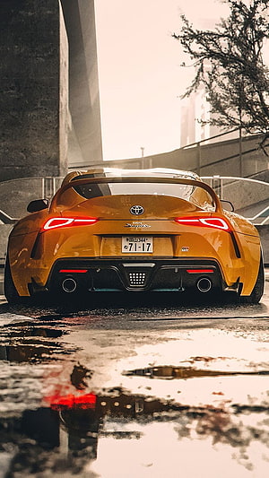 Rear View of a Golden Toyota Supra Parked on Wet Urban Street with Reflections HD phone wallpaper