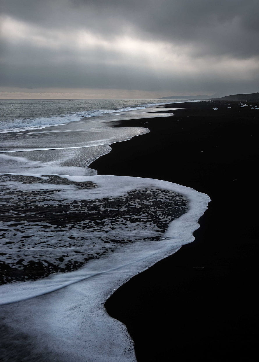 Moody Black Sand Beach with White Sea Foam Under Overcast Sky HD phone wallpaper