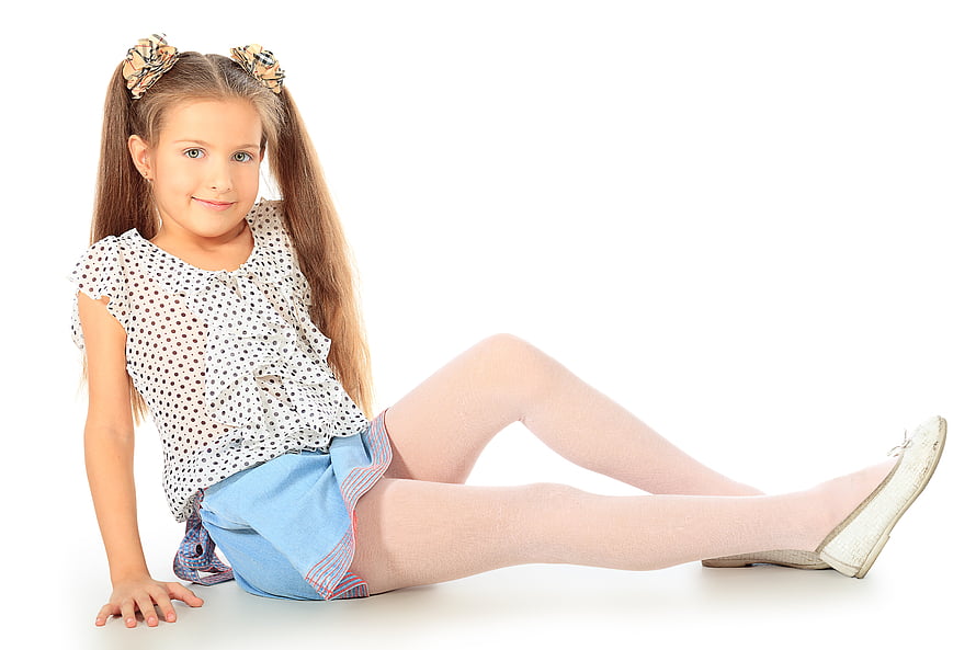 Young girl with pigtails and polka dot top sitting on white studio background HD wallpaper