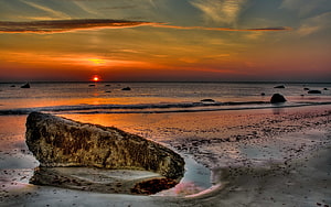 Vivid Orange Sunset Over Calm Ocean With Large Beach Rock And Wet Sand Reflections HD wallpaper
