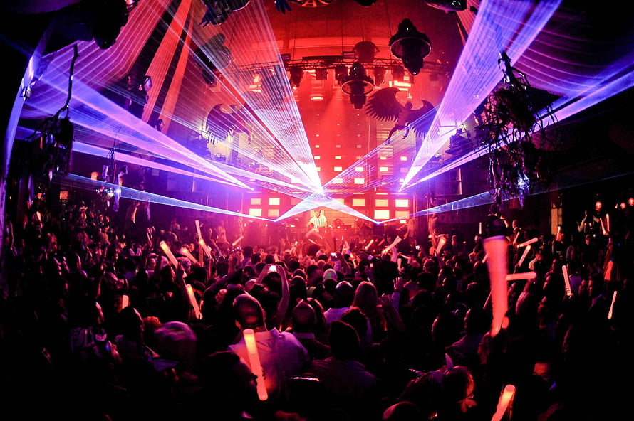 Vibrant nightclub crowd with dramatic purple and red laser beams cutting through the dark venue HD wallpaper