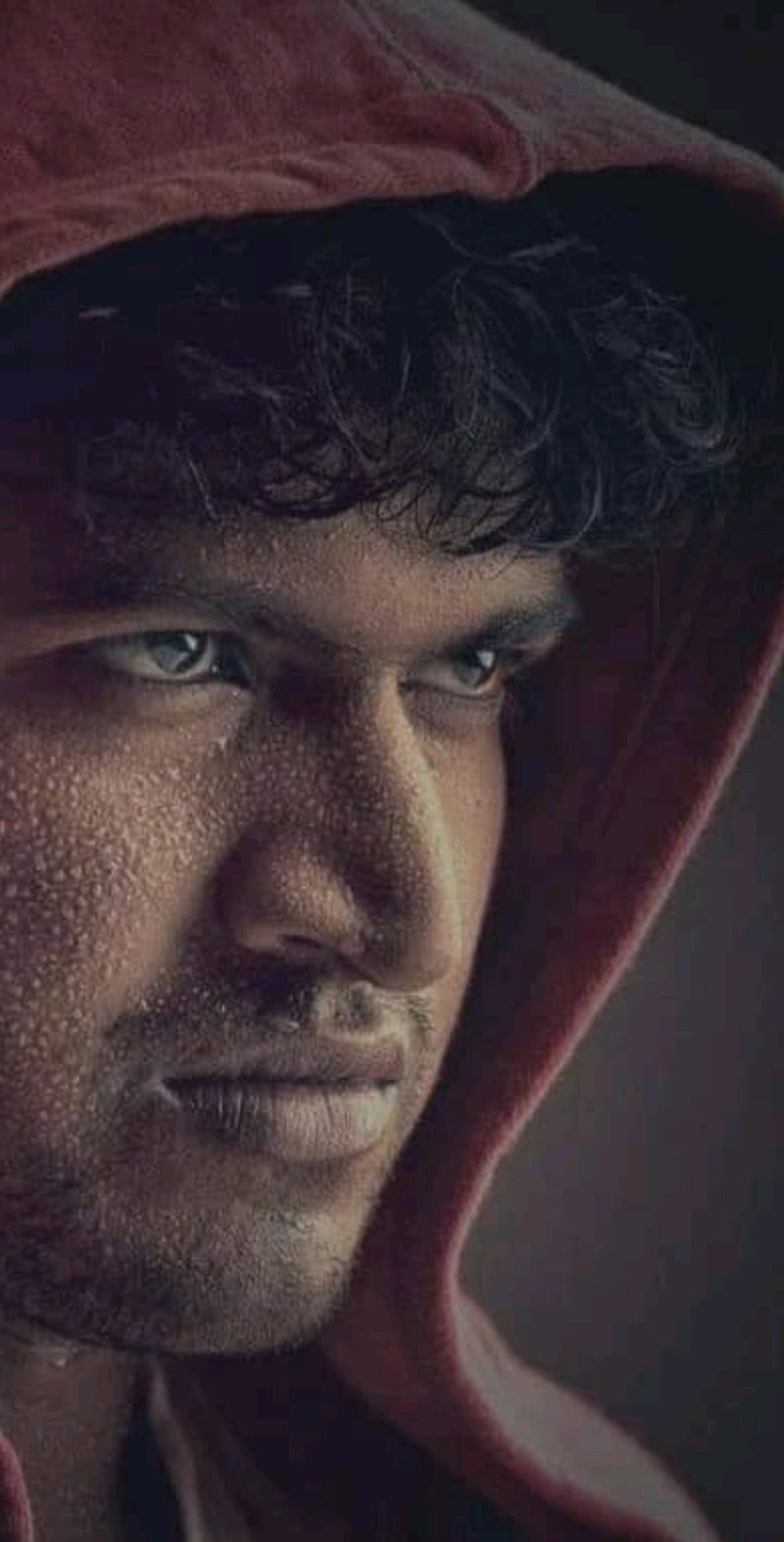 Puneeth Rajkumar Intense Portrait in Red Hoodie with Dramatic Lighting HD phone wallpaper
