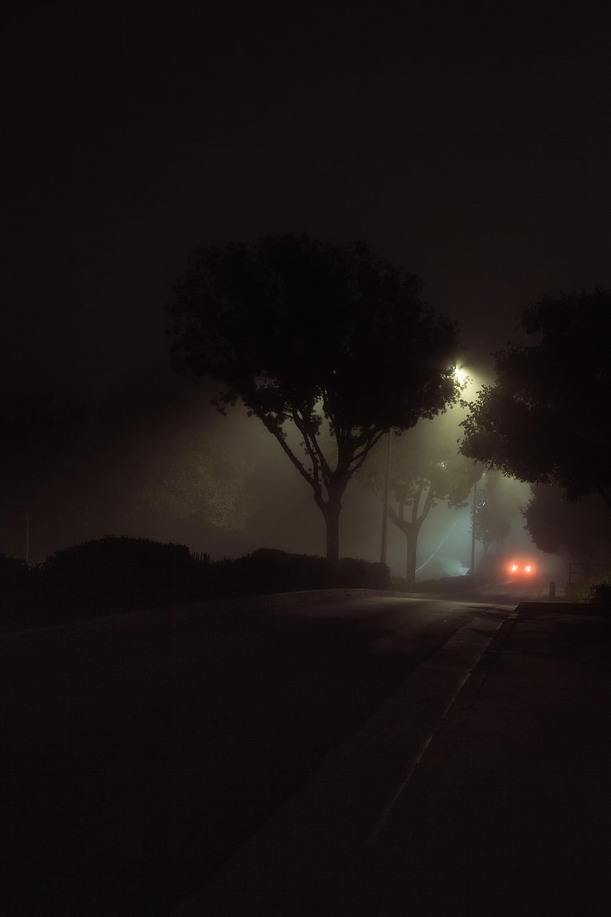 Eerie Foggy Night Street Scene With Glowing Streetlights And Distant Car Headlights HD phone wallpaper