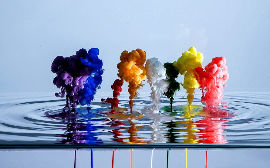 Vibrant multicolored paint drops blooming in clear water with ripples and reflections HD wallpaper