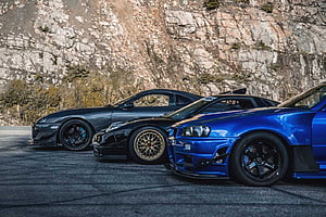 JDM Legends Supra, NSX, and R34 GTR Parked Against a Rocky Cliff Face HD wallpaper