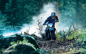 Off-road motorcyclist splashing through a muddy forest trail HD wallpaper