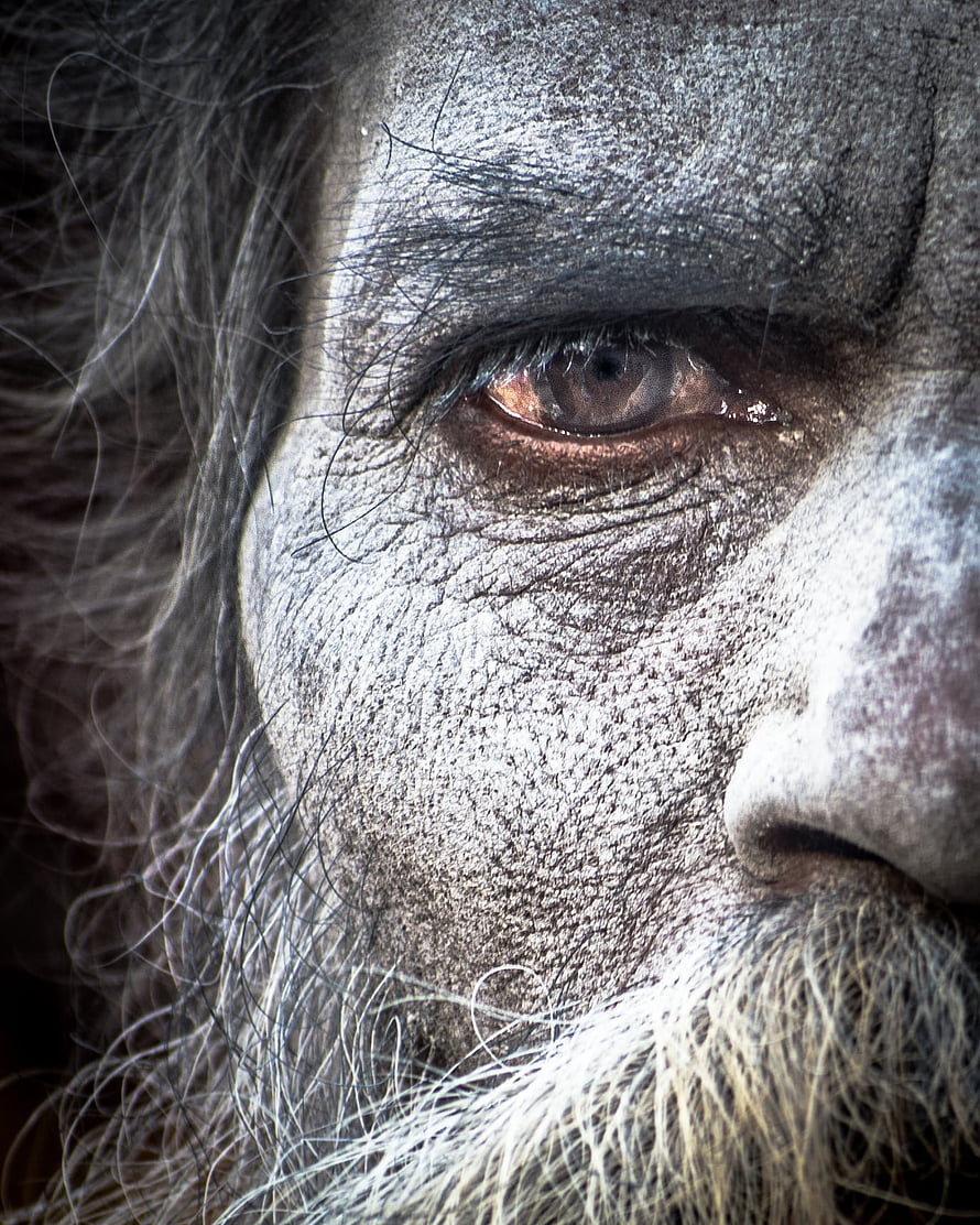 Close-up portrait of an Aghori with ash-covered face and intense gaze HD phone wallpaper