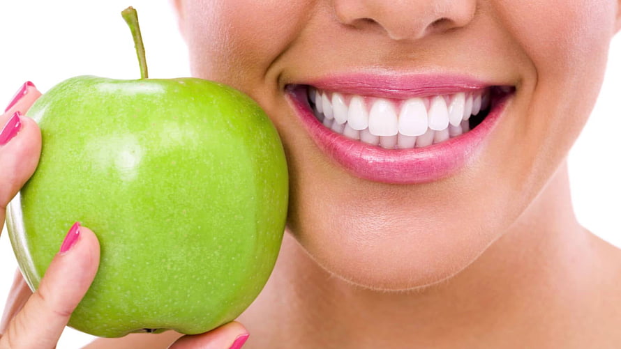 Close-up of a smiling woman holding a fresh green apple against a clean white background HD wallpaper