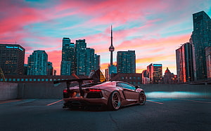 Lamborghini Aventador with rear wing parked on a rooftop overlooking the Toronto skyline at sunset HD wallpaper
