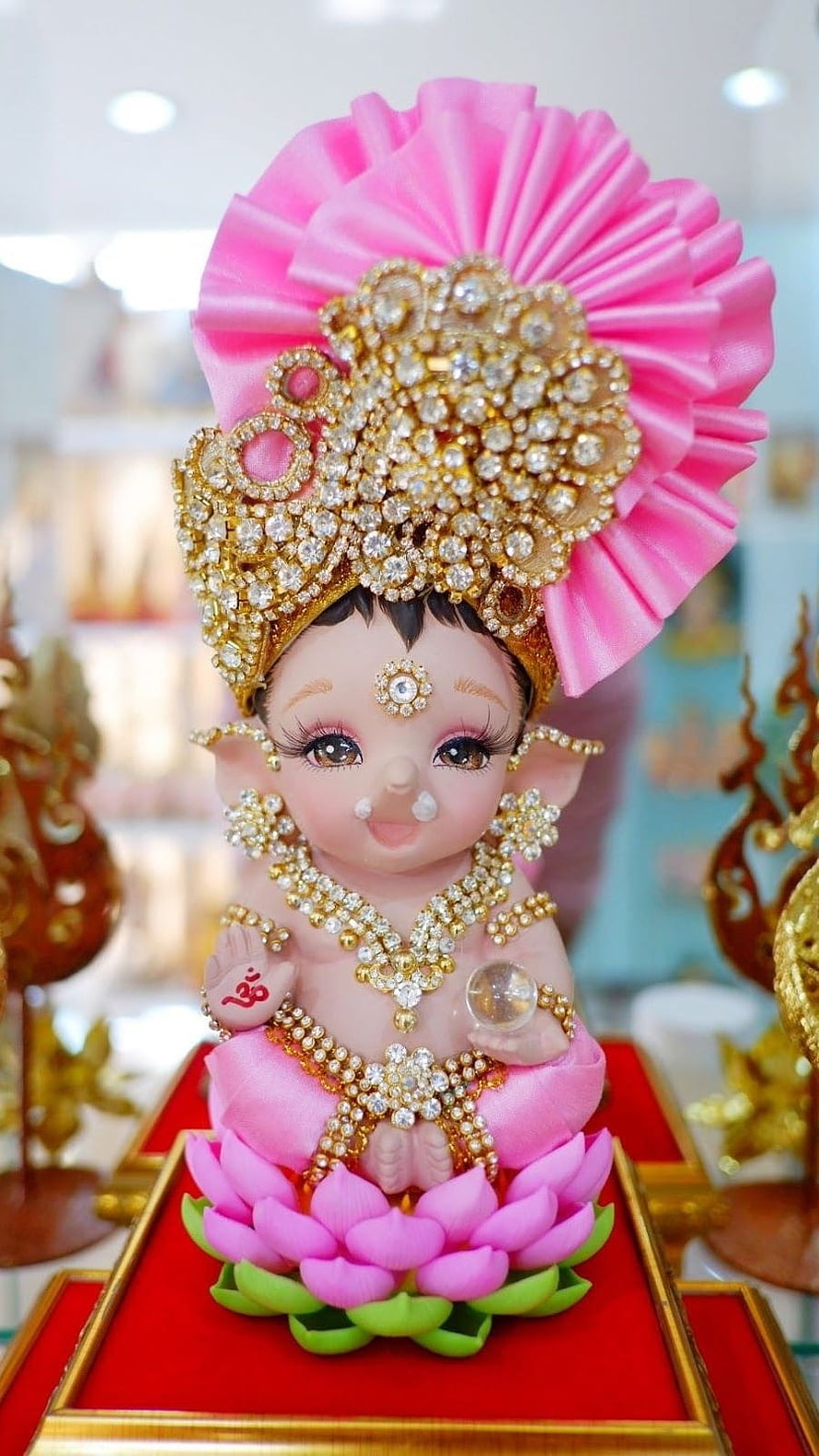 Ornate Baby Ganesha Idol Seated on Pink Lotus with Crystal Crown and Gold Jewelry HD phone wallpaper