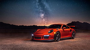 Orange Porsche 911 GT3 RS parked in a desert under a starry night sky with the Milky Way HD wallpaper