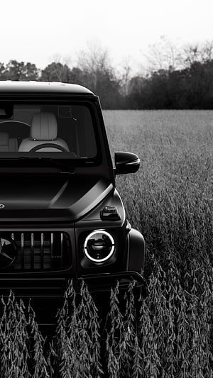 Black Mercedes-Benz G-Class AMG parked in a field with dramatic monochrome lighting HD phone wallpaper