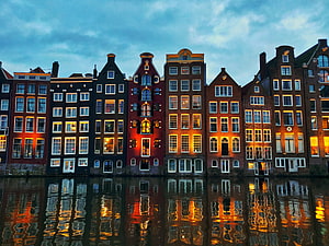 Amsterdam Canal Houses at Dusk with Warm Window Lights and Water Reflections HD wallpaper