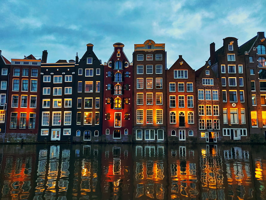 Amsterdam Canal Houses at Dusk with Warm Window Lights and Water Reflections HD wallpaper