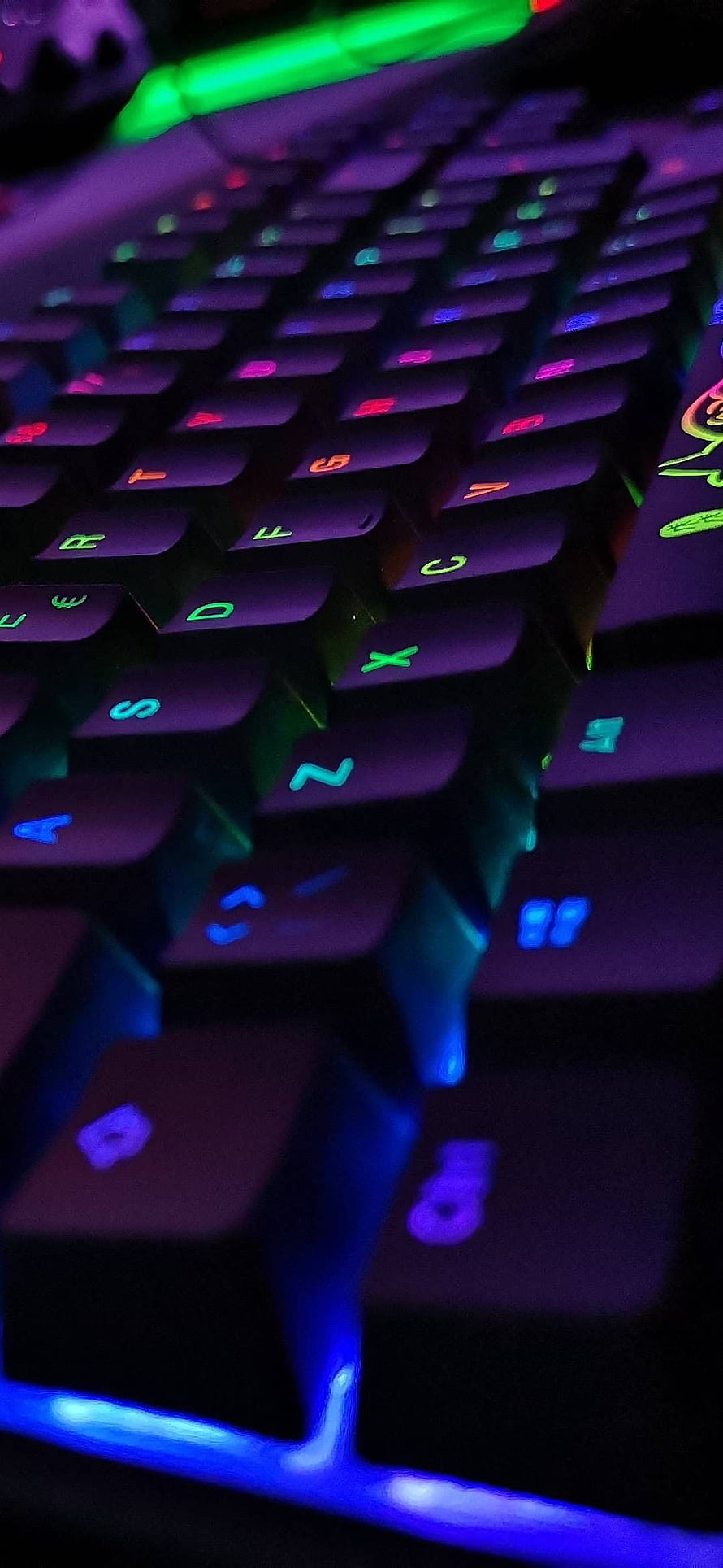 Close-up of RGB backlit gaming keyboard with vibrant multicolor keycaps in a dark setting HD phone wallpaper