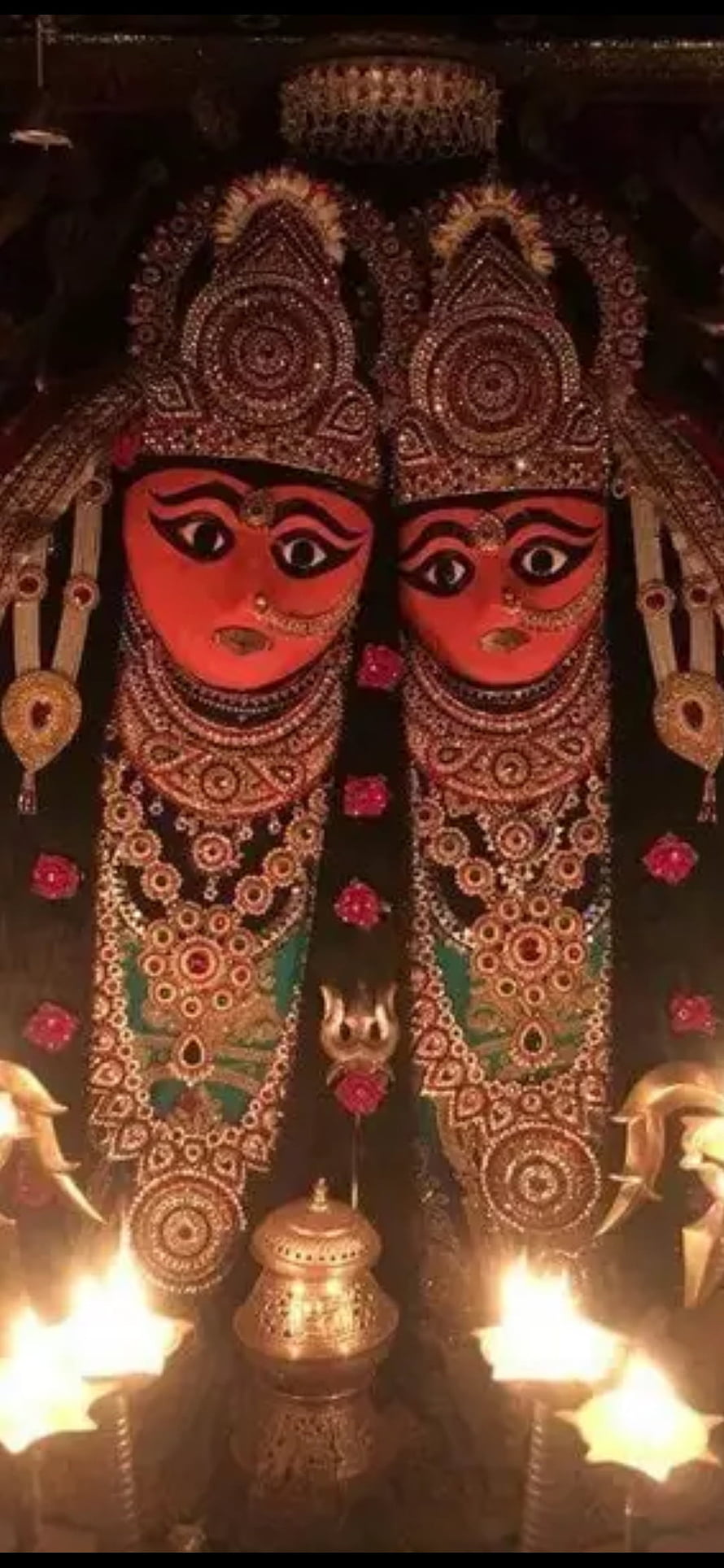 Chamunda Maa ornate idol adorned in gold jewelry with lit oil lamps and red flowers HD phone wallpaper