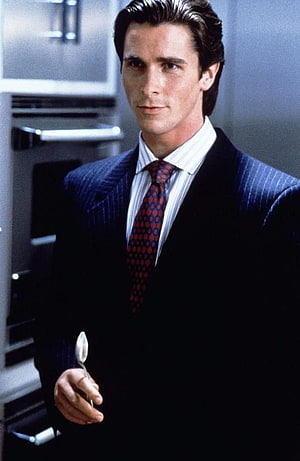 Patrick Bateman in a dark pinstripe suit holding a spoon in a modern kitchen, American Psycho , Patrick Bateman HD phone wallpaper