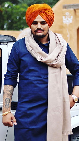 Sidhu Moose Wala in a blue kurta with an orange turban and beige scarf HD phone wallpaper