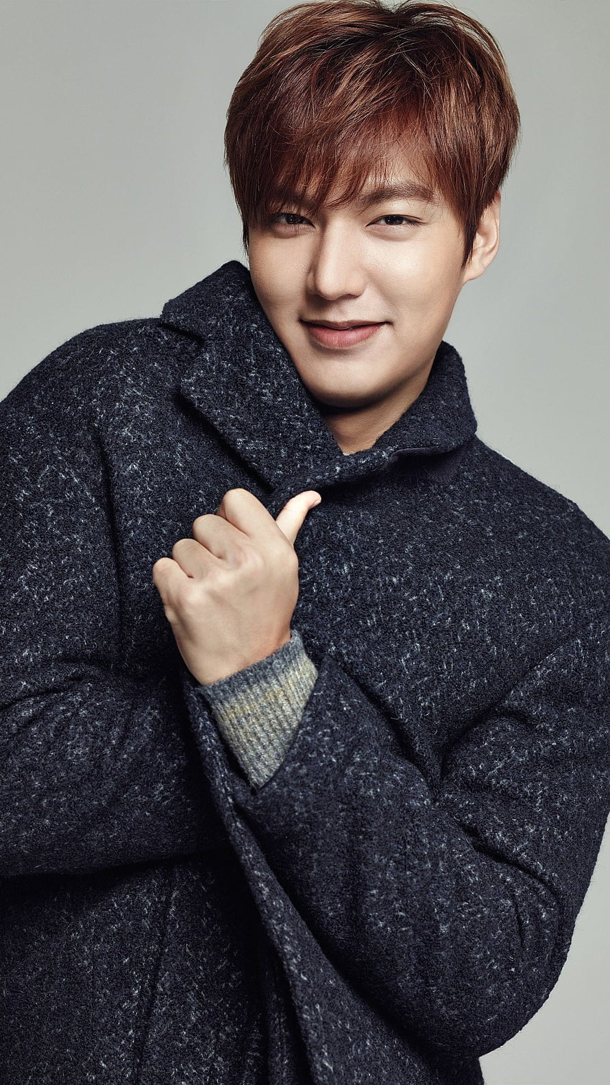 Lee Min Ho in a dark wool coat with a soft smile against a neutral studio backdrop HD phone wallpaper