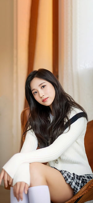 Mina from TWICE in a white cardigan and plaid skirt with soft indoor lighting HD phone wallpaper