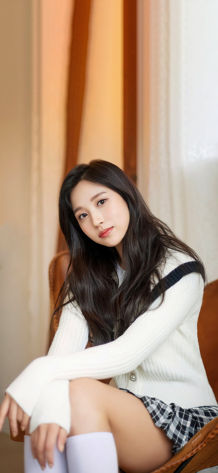 Mina from TWICE in a white cardigan and plaid skirt with soft indoor lighting HD phone wallpaper