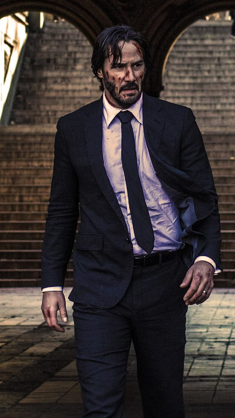 John Wick in a dark suit with a bloodied face standing in a stone archway HD phone wallpaper
