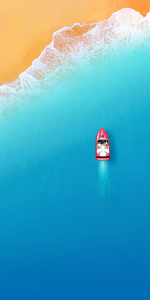 Aerial View of a Red Speedboat Cruising Through Turquoise Ocean Water Near a Sandy Beach HD phone wallpaper
