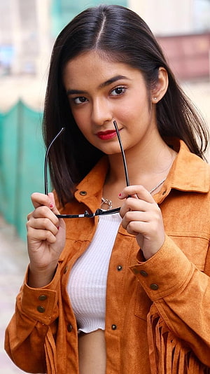 Anushka Sen in a Suede Jacket Holding Glasses with Red Lipstick HD phone wallpaper