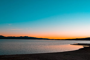 Serene Lake Sunset with Distant Hills and Gradient Sky HD wallpaper