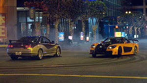 Two modified sports cars drifting on a neon-lit Tokyo street at night HD wallpaper