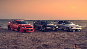 Three Nissan Skyline GT-R R34 coupes parked on a desert plain at sunset HD wallpaper
