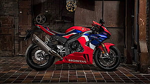 Honda CBR1000RR-R Fireblade SP sportbike in red and blue livery parked in an industrial garage setting HD wallpaper