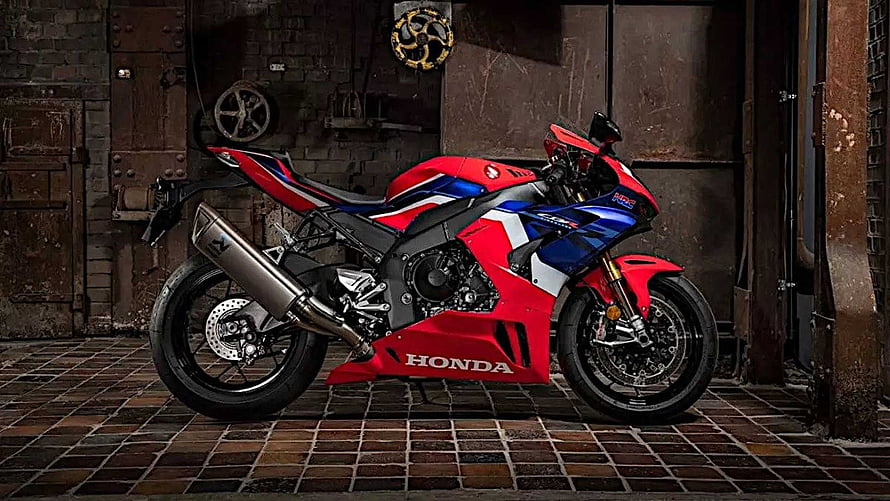 Honda CBR1000RR-R Fireblade SP sportbike in red and blue livery parked in an industrial garage setting HD wallpaper