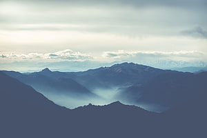 Layered Mountain Ranges with Valley Mist and Distant Snow Peaks HD wallpaper
