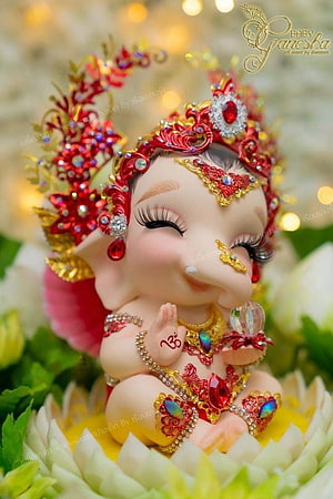 Baby Ganesha Figurine Adorned in Red and Gold Jewelry Seated on Lotus HD phone wallpaper