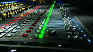 Professional Audio Mixing Console with Glowing Faders and Control Knobs in a Dark Studio Setting HD wallpaper