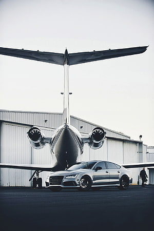 Audi RS7 Sportback parked in front of a private jet at an airport hangar HD phone wallpaper