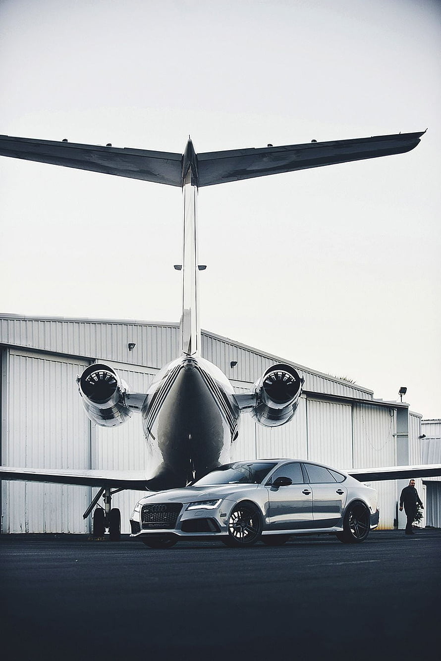 Audi RS7 Sportback parked in front of a private jet at an airport hangar HD phone wallpaper