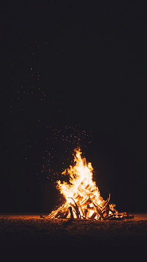 Dramatic Campfire Burning on a Dark Night with Rising Sparks and Glowing Embers HD phone wallpaper