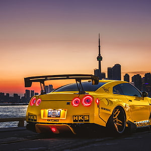 Yellow Nissan GT-R Widebody with HKS and Bride Badges Parked Against Toronto Skyline at Sunset HD phone wallpaper