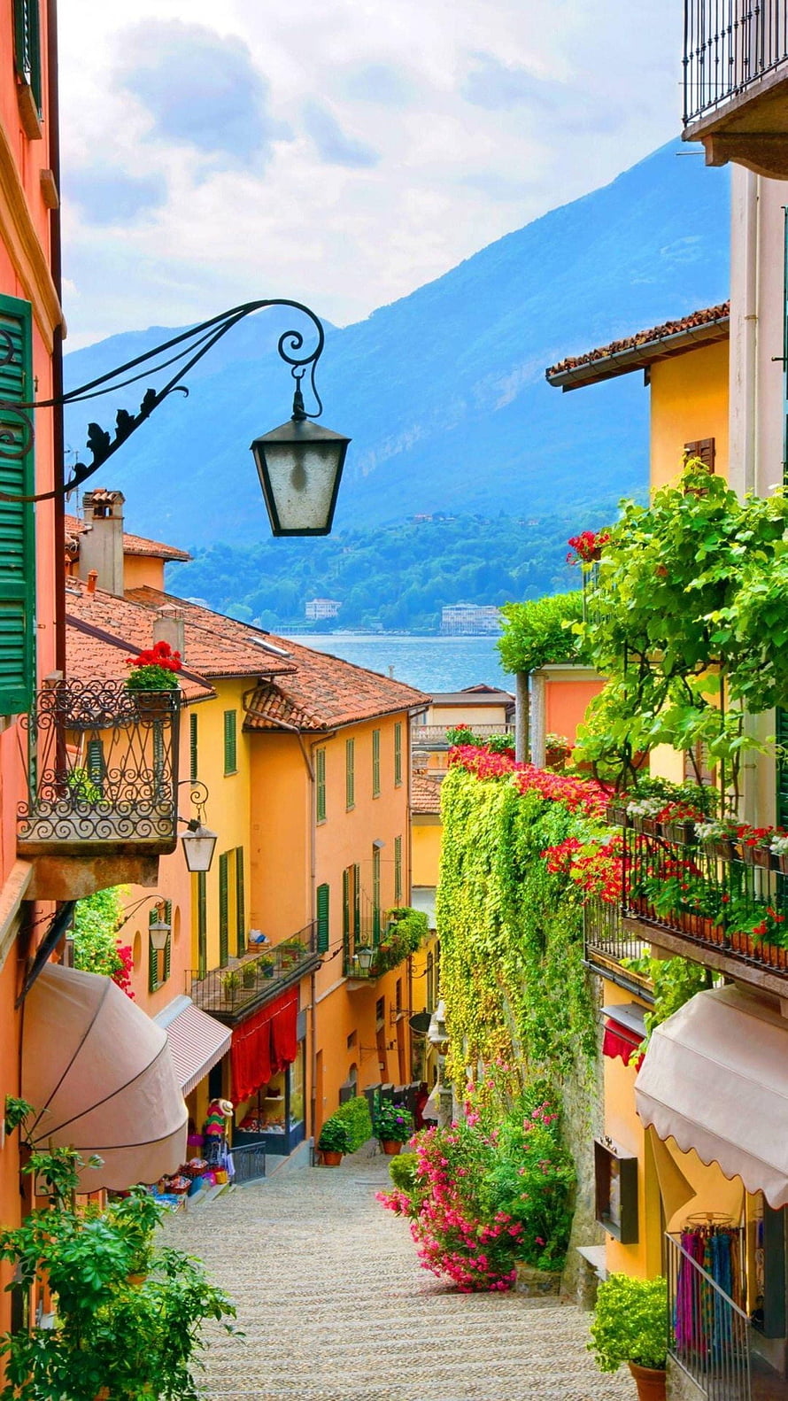 Colorful Italian Village Street with Cobblestone Path and Lake View HD phone wallpaper