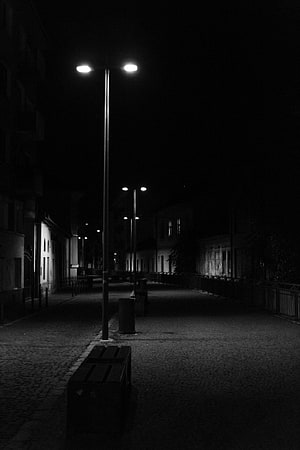 Moody Black and White Night Street Scene with Glowing Lamps and Cobblestone Path HD phone wallpaper