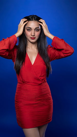 Kiara Advani in a red satin dress posing against a blue studio backdrop HD phone wallpaper