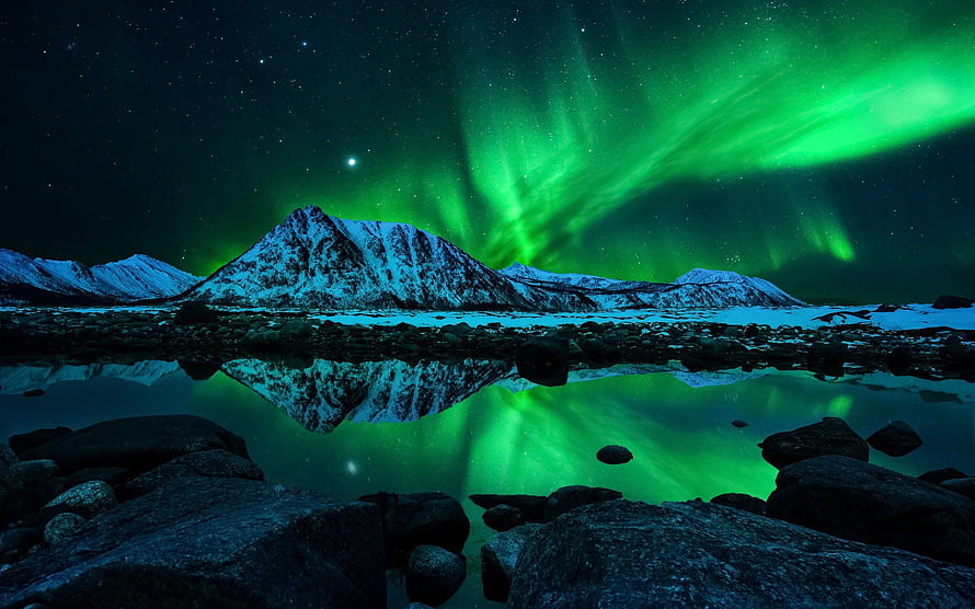 Vibrant green aurora borealis dancing over snow-capped mountains reflected in a calm alpine lake at night HD wallpaper