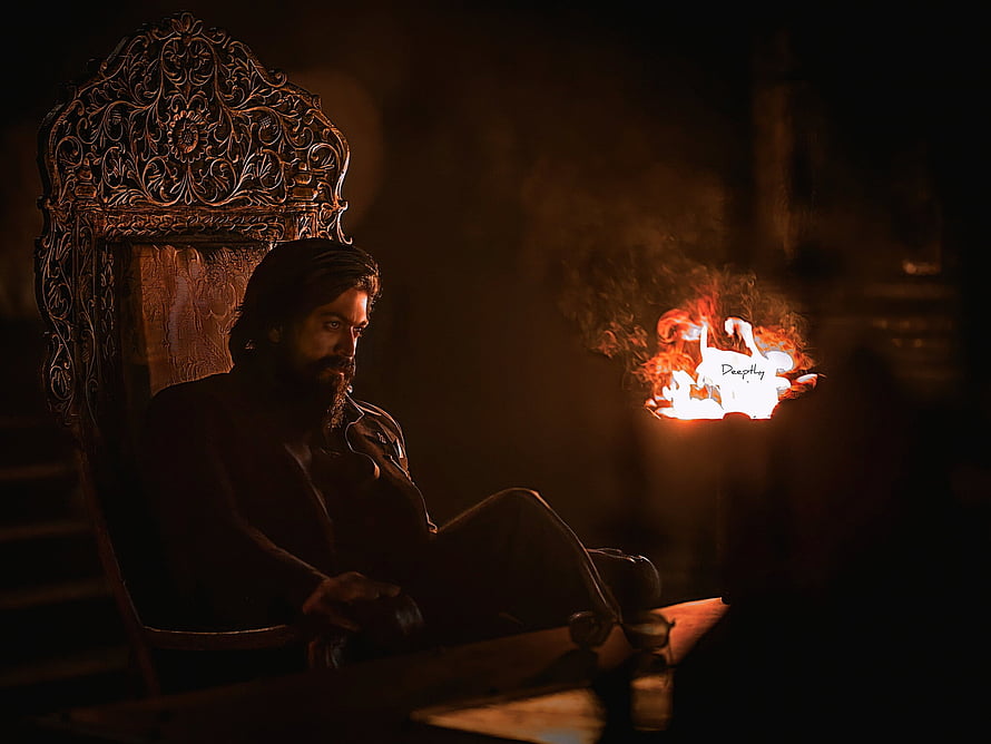 Yash in KGF seated on ornate throne beside a burning paper in dim cinematic lighting HD wallpaper